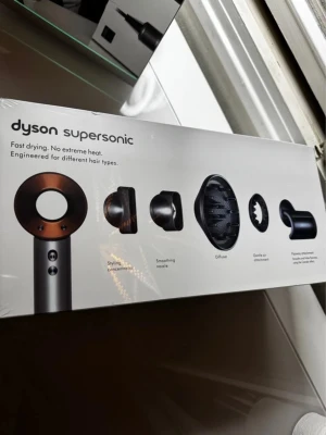 Dyson Supersonic hair dryer (oöppnad) med kvitto! - Dyson Supersonic hårfön med fem stylingtillbehör: styling concentrator, smoothing nozzle, diffuser, gentle air attachment och flyaway attachment. Designad för snabb torkning utan extrem värme och passar olika hårtyper.