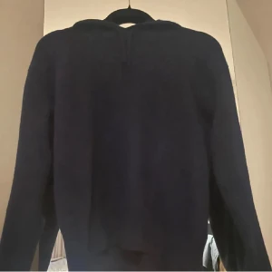 Mörkblå kashmir med huva - Mysig mörkblå kashmir tröja med huva och långa ärmar. Perfekt för kyliga dagar och enkel att matcha med jeans eller mjukisbyxor. Klassisk modell med relaxed fit och skön känsla.