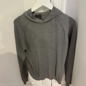 Stickad Grå hoodie från Oscar Jacobson  - Snygg grå hoodie från Oscar Jacobson i 100% bomull. Klassisk modell med huva och långa ärmar, perfekt för en chill och stilren look. Enkel och tidlös design som funkar året runt. Skicket är som nyt. Knappt kommit till andvänding. 