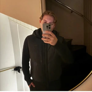 Svart cardigan från BOSS, storlek M - Säljer en svart cardigan från BOSS i storlek M. Jackan har stickade ärmar, huva och dragkedja framtill. Snygg och stilren design med BOSS-logga på bröstet. Perfekt för dig som vill ha en varm och trendig jacka med schyssta detaljer.  Priset kan diskuteras 