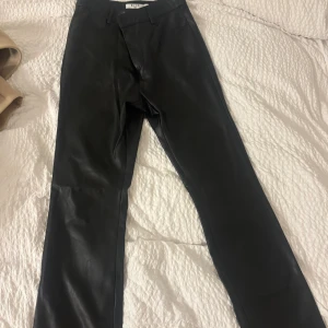 Svarta skinnbyxor från NA-KD -  svarta bootcut skinnbyxor från NA-KD i strl 36 Byxorna har hällor för bälte, fickor fram och bak samt stängs med dragkedja och knapp. Men byxorna är alldeles för stora för mig 