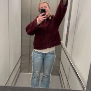 Blå bootcut jeans med fransar - Säljer ett par ljusblå bootcut jeans med fransade sidor längs hela benen. Jeansen har klassisk femficksdesign och är tillverkade i denim. Perfekta för dig som vill sticka ut med en unik detalj på dina jeans. Jag har sytt upp jeansen och är lite för korta för mig som är 166 cm men det finns en bit att spretta upp om man vill göra de längre