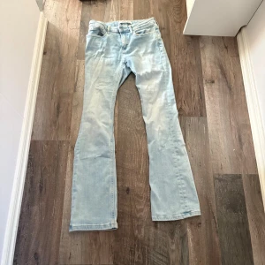 Ljusblå bootcut jeans - Säljer ett par ljusblå jeans med bootcut passform. Jeansen har klassisk femficksdesign och är tillverkade i denim. Perfekta för dig som gillar en retroinspirerad look med utsvängda ben.