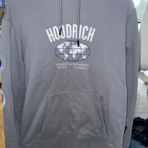 Grå hoodie  Hoodrich - Snygg grå hoodie från Hoodrich med stort tryck på bröstet och detaljer på ärmen.  Inga fläckar eller hål, skick 9/10. Size L. Om du har fler frågor eller är intresserad, skriv privat