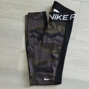 Nike Pro camo leggings - Nike Pro leggings med coolt camouflage-mönster.Sitter tight och är perfekta för träning. Går till anklarna på mig som är 164 xm lång.Jätte fint skick förutom att jag klippt bort tvättlappen.💕