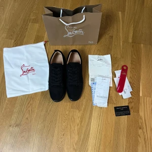 Christian Louboutin suede - Snygga svarta sneakers från Christian Louboutin i mocka med klassisk röd sula. Skorna har rund tå, svarta snören och diskret branding på insidan. Perfekta för dig som vill sticka ut med exklusiv stil och detaljer. PASSAR 44
