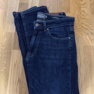 Mörkblå jeans från Dressmann Regular Fit - Snygga mörkblå jeans från Dressmann i regular fit. Klassisk femficksmodell med kontrastsömmar och knappgylf. Jeansen har en rak passform och är tillverkade i slitstarkt denimtyg som ger en tidlös look.