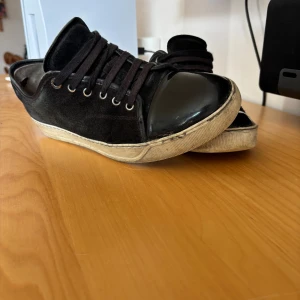 Svarta sneakers från Lanvin med lackad tå - Säljer ett par Lanvin sneakers i storlek 41.            Skick 7,5/10.        Storlek 41.          Har varken box eller kvitto men köpte för några månader sedan på merchswedens hemsida
