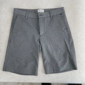 Grå shorts från Only & Sons W30 - Snygga grå shorts från Only & Sons i klassisk modell med bälteshällor och sidfickor. Perfekta för sommaren med sin stilrena look och bekväma passform. Materialet är mjukt och stretchigt, vilket gör dem riktigt sköna att bära.