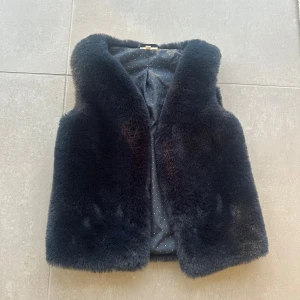 Mörkblå pälsväst från PompDeLux  - Fluffig och mjuk mörkblå pälsväst. Västen har en klassisk rak passform och är perfekt för att addera lite extra edge till din outfit.