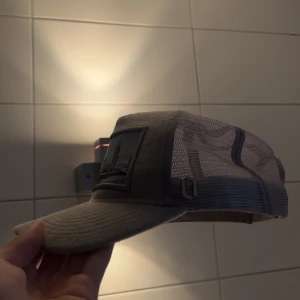 Grå meshkeps från Onecap - Säljer en grå keps från Onecap med mesh på sidorna och baksidan för extra ventilation. Framsidan har en stor patch med Londonmotiv och text. Justerbar snapback baktill. Perfekt för dig som vill ha en stilren och cool keps med unik detalj.Om du har några frågor eller funderingar så kan ni kontakta mig😃