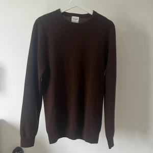 Brun kashmirtröja från John Henric - Mörkbrun rundhalsad tröja i lyxig kashmir från John Henric. Klassisk modell med ribbade muddar och lång ärm, perfekt att bära över skjorta för en clean och stilren look. Supermjuk och skön mot huden. Modellen är 180cm.