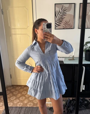 Ljusblå skjortklänning från Zara - Supersöt ljusblå skjortklänning från Zara med krage, v-ringning och långa ärmar. Klänningen har volanger i flera lager och en luftig passform. Perfekt att styla med andra ljusa färger (sista bilden)😚 Så fin men kommer tyvärr inte till användning. Använd gärna KÖP NU💗 