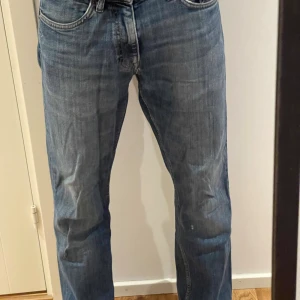 Blå jeans från Gant - Säljer ett par klassiska blå jeans från Gant med raka ben och normal passform. Jeansen har fem fickor, bälteshällor och Gant-logga på myntfickan. Materialet är slitstarkt denim i bomull och färgen är mellanblå med lätt tvättad look. Byxorna är omsydda imellan bena eftersom de sprack men inget som syns utifrån! Även längst ner på benen