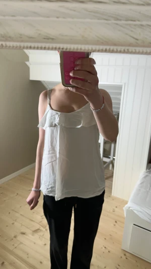 Vit volang-linnetopp från Esprit - Säljer en söt vit linnetopp från Esprit med tunna axelband och volangdetalj över bysten. Toppen är ärmlös och har en luftig passform, perfekt för varma dagar. Materialet är mjukt och lätt, vilket gör den superbekväm att bära.