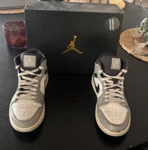 Nike Air Jordan 1 Mid grå/vit - Säljer ett par Nike Air Jordan 1 Mid i grått, vitt och svart. Skorna är köpta på restocks för cirka 2299 kr, skorna är i fint skick och box ingår, hör av er vid frågor.