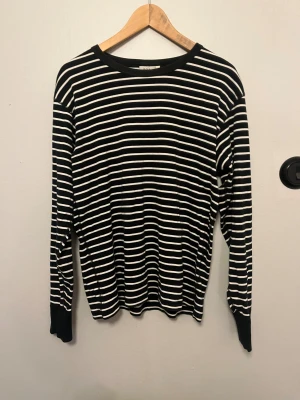 Svartvit randig tröja Polarn O. Pyret - Randig långärmad tröja från Polarn O. Pyret i svart och vitt. Klassisk rund hals och mjukt material i bomull. Perfekt för dig som gillar enkel och stilren design med lite edge. Passar dig som vill ha en normal passform och snygga kontraster.