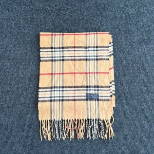 Burberry scarf - Burberry-scarf som är 100% äkta. Mindre defekter kan förekomma enligt bild men inget märkvärdigt då de är vintage. Snabb leverans och trygg handel då vi har 7 års erfarenhet i branschen. Vid frågor eller bud, skicka gärna ett meddelande. 1002