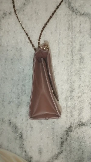 Brun quiltad axelväska med kedja - Snygg brun axelväska med quiltad design och guldfärgad kedja som axelrem. Väskan har ett triangulärt lock med magnetknäppning och insidan är rymlig för det viktigaste. Perfekt för dig som gillar stilrena detaljer och en modern look.