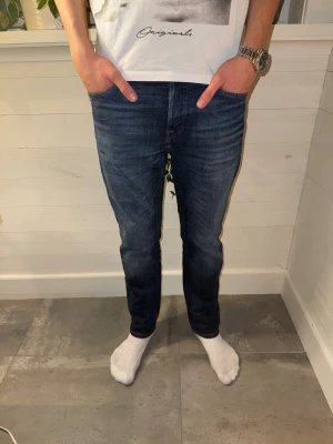 Mörkblåa jeans från Jack & Jones - Säljer ett par klassiska blå jeans från Jack & Jones med snygg tvätt och kontrastsömmar. Modellen har normal passform. Skinnpatch med logga bak i midjan. Perfekta för dig som gillar stilrena och bekväma jeans.