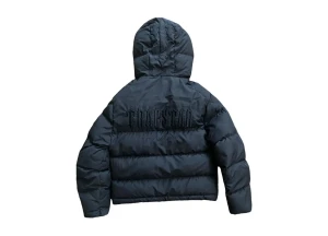 Svart pufferjacka från Trapstar - Svart pufferjacka från Trapstar med broderad logga på ryggen och huva. Jackan har en boxig passform, två stora fickor framtill och dragkedja. Perfekt för kalla dagar när du vill ha en streetig look. Strl L men passar även Xl dragkedjan har smått tappat färg men absolut inget man märker av när den sitter på