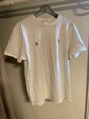 Axel Arigato T-shirt – Storlek M - Säljer en vit Axel Arigato T-shirt i storlek M. Tröjan är i okej begagnat skick med mindre tecken på användning, men fortfarande fräsch och fullt användbar. Broderade detaljer på bröstet samt liten Axel Arigato-tag på sidan.