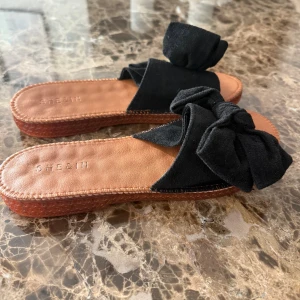 Svarta sandaler med rosett från SHEIN - Snygga sandaler från SHEIN med svart ovandel i mockaliknande material och stor rosett som detalj. Sulan är brun och platt, perfekt för varma dagar. Enkla att matcha till sommarens outfits.