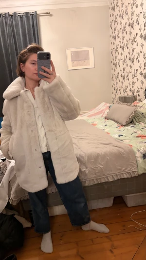 Vit pälsjacka från H&M - Säljer en fluffig och oversized vit pälsjacka från H&M. Jackan har bred krage, dolda knappar framtill och två fickor. Perfekt för dig som vill ha en mysig och trendig look under kalla dagar.