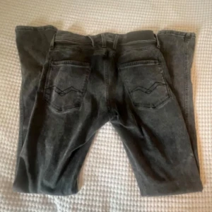 Replay Anbass svarta slim jeans - Säljer ett par Replay Anbass jeans i svart  färg, slim fit med klassisk femficksdesign och snygga detaljer på bakfickorna. Jeansen är tillverkade i stretchigt jeansmaterial och har knapp och dragkedja framtill.    28-32