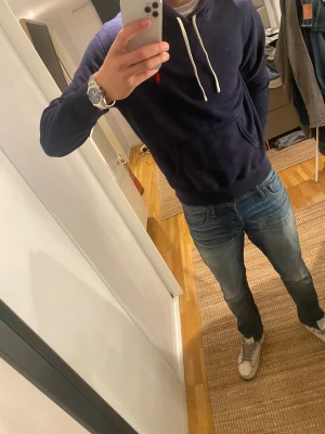 Mörkblå hoodie från Polo Ralph Lauren - Snygg mörkblå hoodie från Polo Ralph Lauren med vit snörning och klassisk röd logga på bröstet. Använd sparsamt och därför i fint skick! Nypris på denna ligger på ca 2000kr Mitt pris: 500