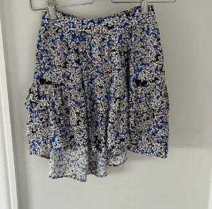 Mönstrad kjol från Zadig & Voltaire - Säljer denna unika kjol från Zadig med ett coolt mönster. Den är i grunden blå men fylld med vita blommor och rosa nyanser, men även små svarta detaljer. Kjolen är köpt på Zadigs hemsida.