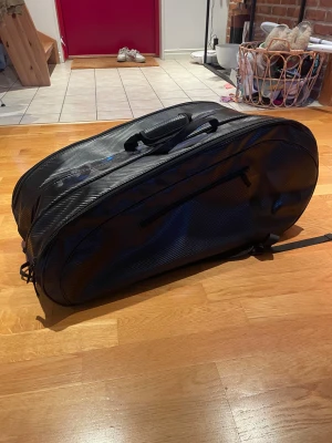 Wilson Tennisväska - Säljer en svart Wilson tennisväska, Racken som syns på bilden ingår ej.