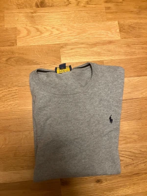 Grå långärmad tröja från Ralph Lauren - Säljer denna feta Ralph Lauren tröjan för ett bra pris. Ett litet  hål vid ryggen sänker priset men inget som syns vid användning. 