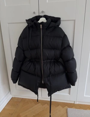 Acne studios Puffer jacket - Säljer en svart acne jacka med huva och snörning i midjan. Super varm, perfekt vinter jacka. Storlek 38. Inga skråmor alls. Väldigt sparsamt använd.  Nypris ca 12 500kr