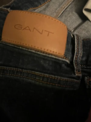 Mörkblå jeans från GANT - Snygga mörkblå jeans från GANT med klassisk femficksdesign och kontrastsömmar. Jeansen har en rak passform och är tillverkade i slitstarkt denimtyg. Läderpatch med GANT-logga baktill och diskret broderad detalj på myntfickan.