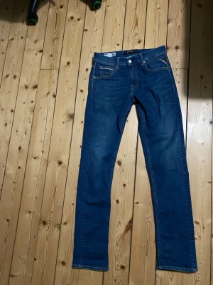 Replay Grover jeans blå straight fit - Säljer ett par snygga Replay Grover jeans i klassisk blå färg. Modellen har straight fit och normal passform, med fem fickor och tydliga kontrastsömmar. Jeansen är tillverkade i bomull och har Replay-logga på bakfickan och etikett i midjan.