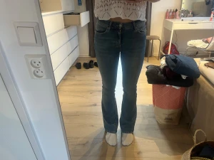 Blå bootcut jeans från Gina Tricot strl 34 - Snygga blå bootcut jeans från Gina Tricot, modell Perfect Jeans. Klassisk femficksdesign, normal passform och normal midja. Jeansen är tillverkade i mjukt denim med lätt tvättad look och har dragkedja och knapp framtill.