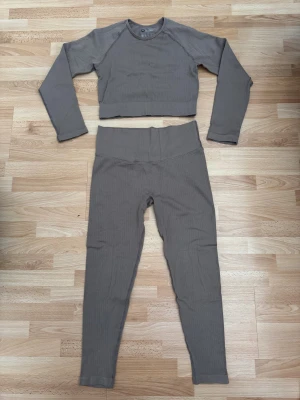 Bruna ribbade leggings med tröja hög midja - Säljer tränning set,  ribbade leggings med hög midja och tröja, tillverkade i stretchigt material (90% polyamid, 10% elastan). De har en tight passform och är perfekta för träning eller chill. Snyggt ribbat mönster och mjuk känsla mot huden.
