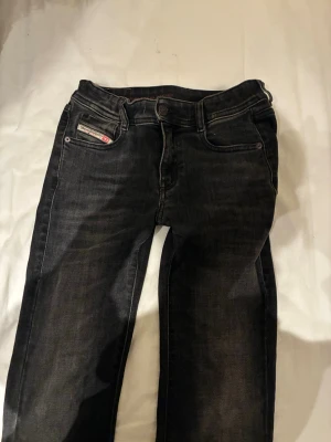Svarta Diesel jeans med utsvängda ben och lågmidjade  - Snygga svarta jeans från Diesel med klassisk femficksdesign och utsvängda ben. Jeansen har en diskret logga på myntfickan och är tillverkade i ett slitstarkt denimtyg. Perfekta för dig som gillar en tidlös och stilren look.
