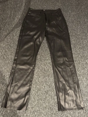 Svarta skinnbyxor - Snygga svarta skinnbyxor med lite utsvängda ben och klassisk passform. Byxorna har en stilren look och passar perfekt till en trendig outfit. Gjorda i skinnimitation för en cool vibe.