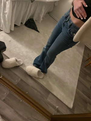 Blå bootcut jeans lågmidjade - Säljer ett par blå bootcut jeans med låg midja. Jeansen har klassisk femficksdesign och är tillverkade i ett mjukt denimtyg. Perfekta för dig som gillar en avslappnad och trendig look.
