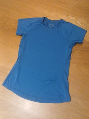 Blå sport t-shirt från H&M  - En enkel blå sport t-shirt från H&M Move med rund hals och korta ärmar. Perfekt för träning och andra sportaktiviteter nu inför våren. Tillverkad i ett lätt och snabbtorkande material som andas. 
