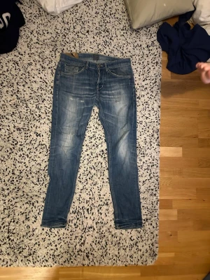 Dondup jeans - Säljer ett par blå dondup jeans med snygga slitningar och tvättade detaljer. Jeansen har klassisk femficksmodell, normal midja och smal passform hela vägen ner. 