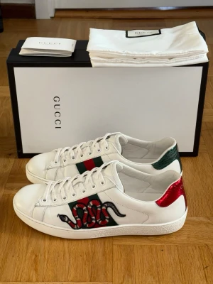Gucci Ace Snake Sneakers - Vita Gucci Ace Snake Skor. Storlek UK 8 vilket motsvarar 42-42,5. Skorna är köpta från en Gucci affär i Paris 2017, nypris ca 8000kr. Låda och skopåse medföljer. Serienummer 456230 8 150. Skriv för fler bilder/frågor.  Fraktas samma dag!📦🚚