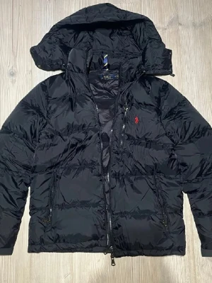 Polo Ralph Lauren Jacka - Tvär fet polo jacka till den med lite schysstare stil. Deeffekter, snöret runt midjan saknas pågrund av att det är trasigt, hål i jackans höger ficka men lagat med en lapp (syns inte).
