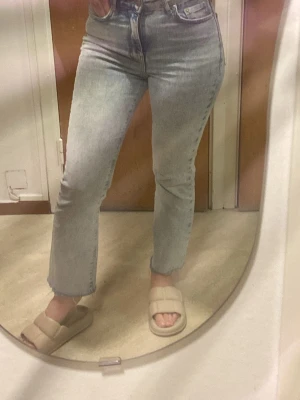 Ljusblå Gina jeans  - Säljer ett par klassiska ljusblå Gina  jeans med hög midja och raka ben. Jeansen har fem fickor, knappgylf och är tillverkade i bomull. Perfekta för en avslappnad och trendig look.