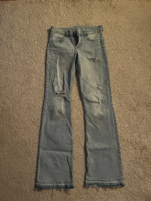 Ljusblå bootcut jeans med slitningar - Säljer ett par jätte snygga low waist bootcut jeans med slitning som tyvärr inte kommer till användning längre, slitningen har jag gjort själv!💕