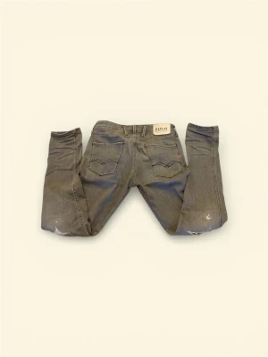 Replay Anbass - Säljer ett par gråa Replay jeans i slim fit-modell. Jeansen har klassisk femficksdesign, snygga slitningar. Använda 1 gång! Nyskick! Ny pris 899. Passar 182-188!