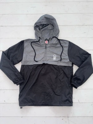 Helt Ny Nottingham Forest Vindjacka - Helt ny svart och grå Nottingham Forest vindjacka, oanvänd , redo att användas, hög kvalité.