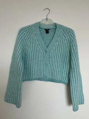 Turkos ribbstickad kofta H&M - Superfin ljusblå ribbstickad kofta från Lindex med v-ringning och knappar framtill. Koftan är croppad och har långa ärmar, perfekt att slänga på sig över en t-shirt eller linne. Mysig och trendig modell för dig som gillar stickade plagg.